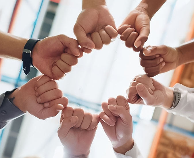 Team of professionals fist bumping in a warehouse, representing Nixxie Trades Sense's dedication to customer service and teamwork.